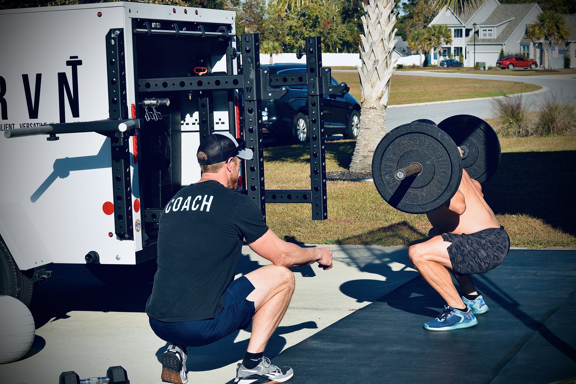 Mobile personal trainer coaching a client in a driveway beside the DRVN trailer